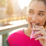 Sportliche Frau isst einen Proteinriegel