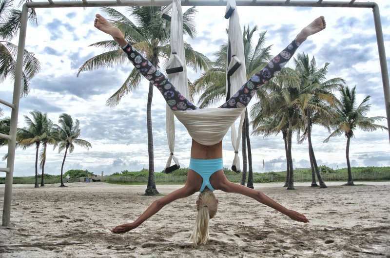 Frau praktiziert Aerial Yoga am Strand 