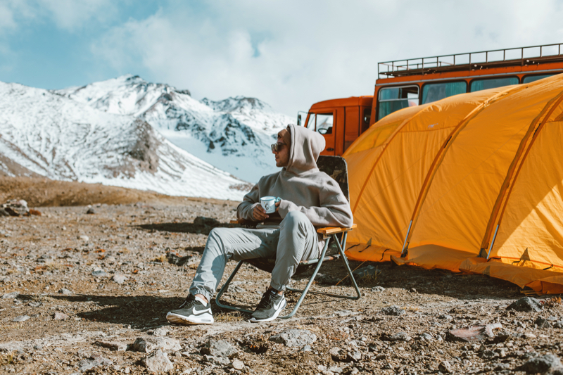 Mann sitzt auf Campingstuhl vor seinem Zelt