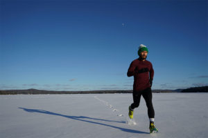 Mann mit Laufhandschuhen laeuft im Schnee