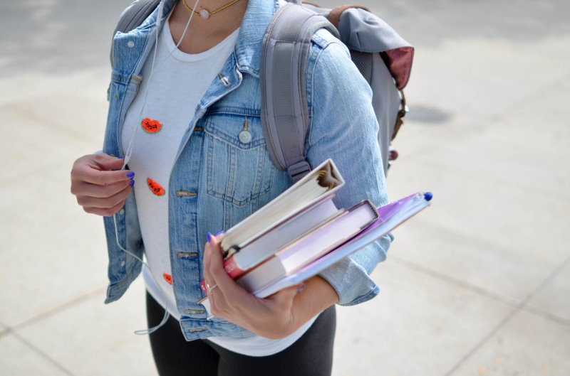 Studentin mit Büchern und Rolltop Rucksack