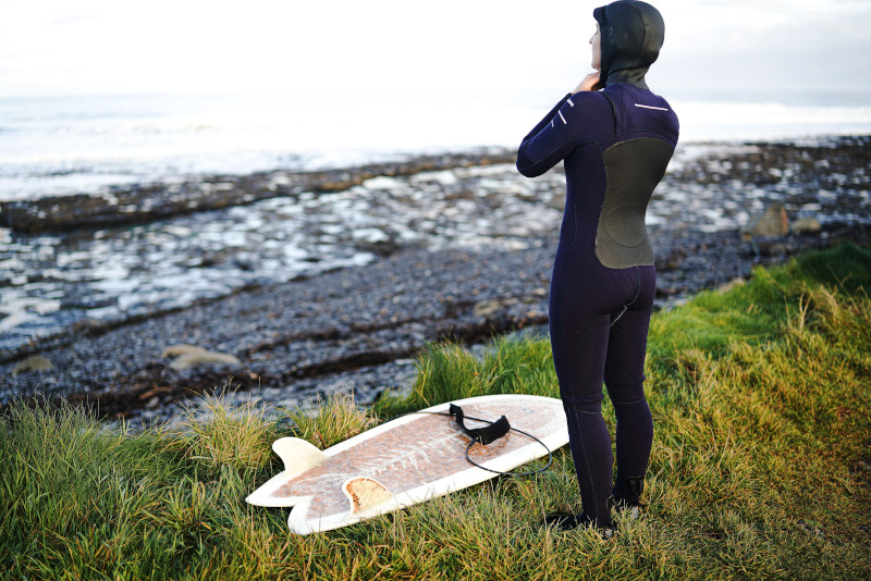 Frau im Winterneoprenanzug und Surfing Zubehör 