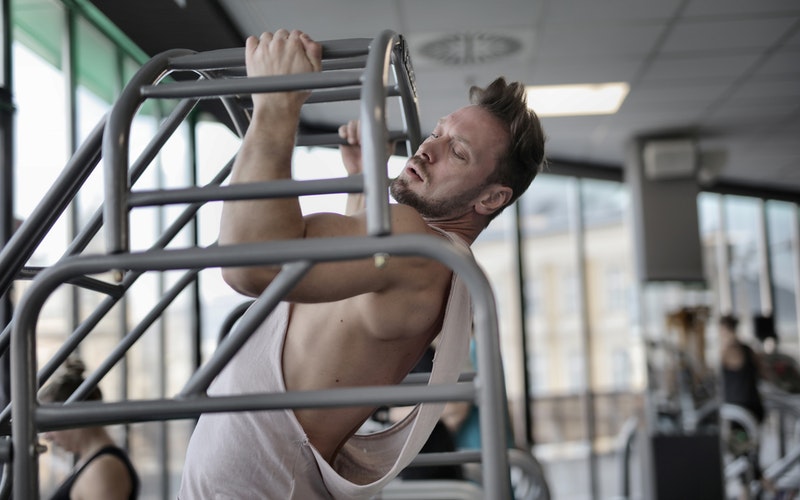 Ein Sportler bei der Ausführung eines Klimmzugs mit neutralem Griff.