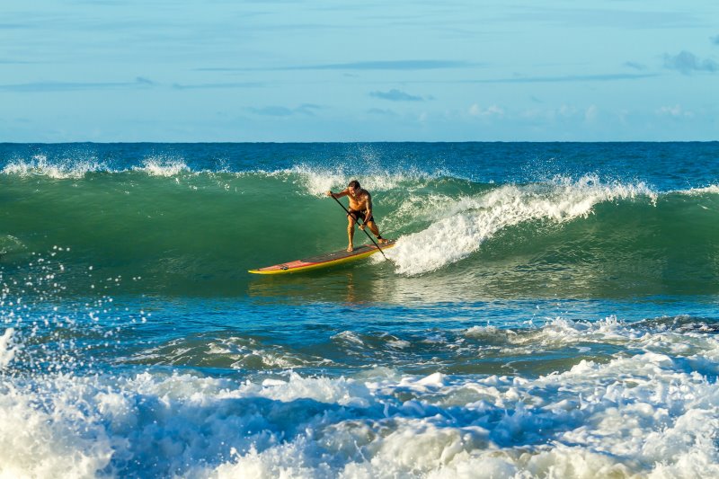 SUP Surfer mit Leash beim Wellenreiten