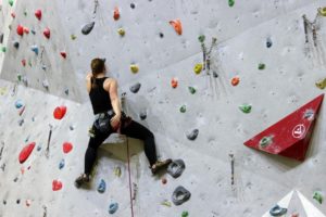 Frau klettert eine Kletterwand hoch