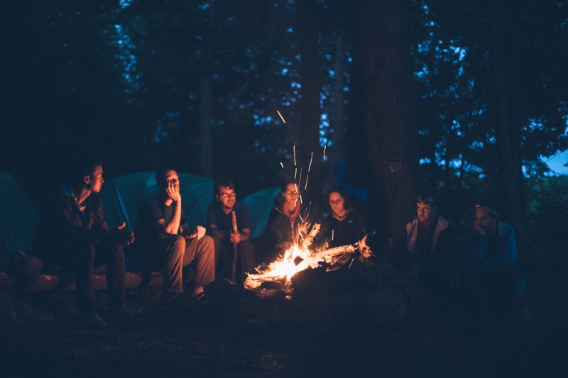 Freunde sitzen beim Campen zusammen am Lagerfeuer