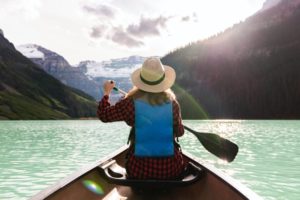 Frau mit Hut auf See und Stechpaddel in der Hand