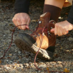 Person schnürt einen Wanderschuh