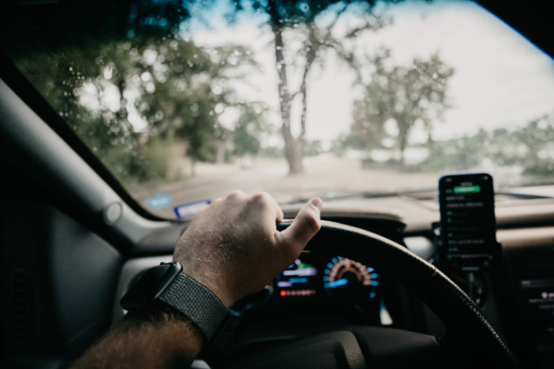 Blick aus einem fahrenden Auto mit Smartphone im Vordergrund