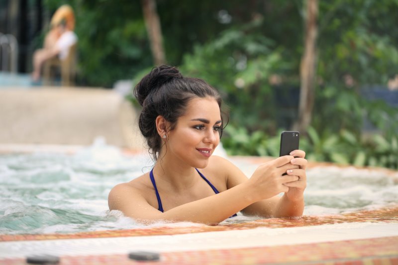 Outdoor Whirlpool, Frau anSmartphone