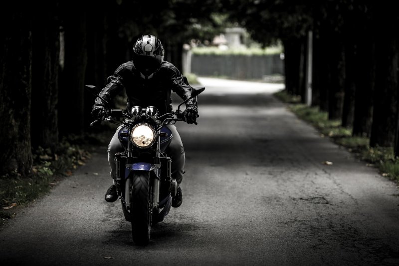 Motorradfahrer fährt auf einer langen geraden Straße 