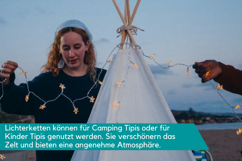 Eine Frau hängt eine Lichterkette auf ein Tipi Zelt