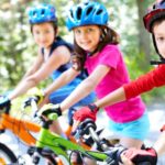 drei Kinder auf Kinderfahrrad sitzend mit Helm