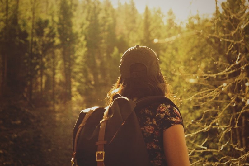 Eine Frau geht gerade mit einem großen Rucksack wandern im Wald 