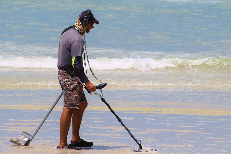 Mann mit einem Metalldetektor am Strand