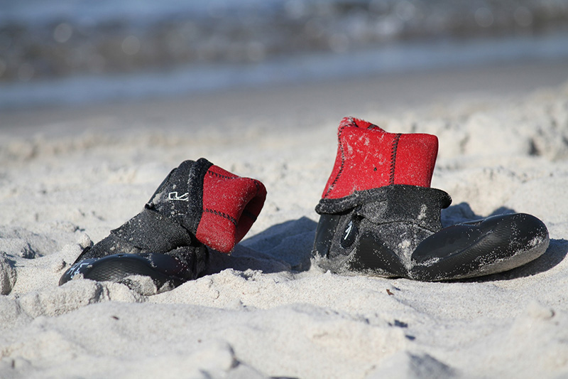 Wasserschuhe stehen im Sand