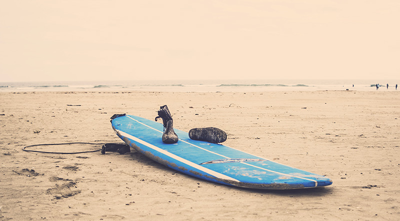 Wasserschuhe am Strand auf einem Surfboard