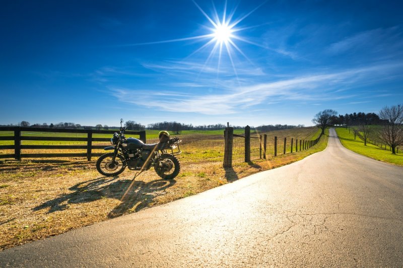 Ein schwarzes Motorrad am Wegesrand in strahlendem Sonnenschein