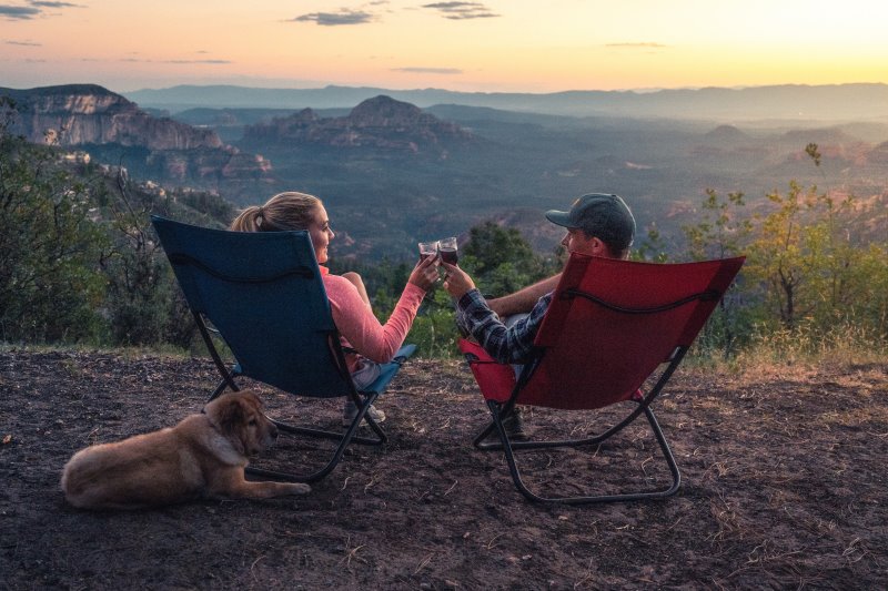 Menschen sitzen auf Campingstühlen mit Hund