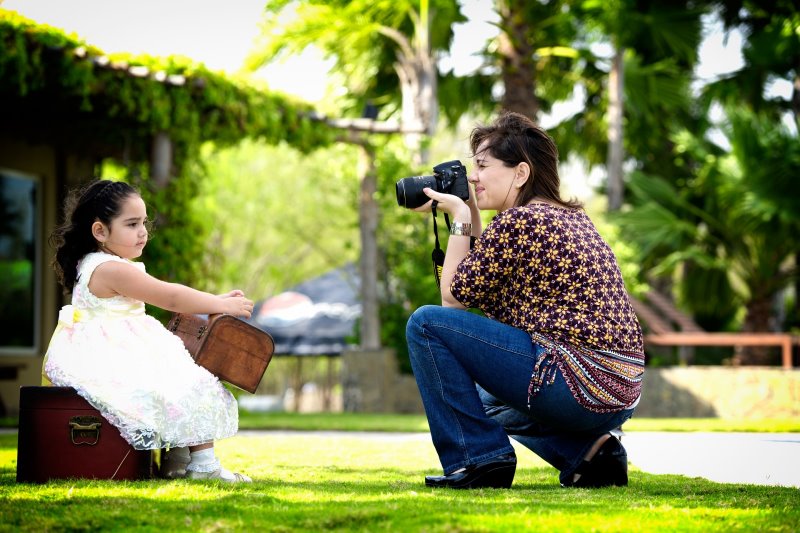 Ein kleines Mädchen wird von einer Dame fotografiert