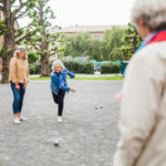 Eine Frau die mit Freunden auf der Straße Boule spielt