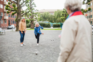 Eine Frau die mit Freunden auf der Straße Boule spielt