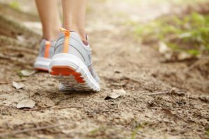 Eine Person walkt in der Natur mit Sportschuhen