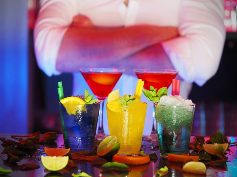 Bartender steht hinter gemixten Cocktails.