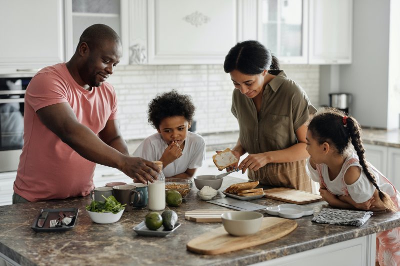 Familie steht in der Küche und kocht.