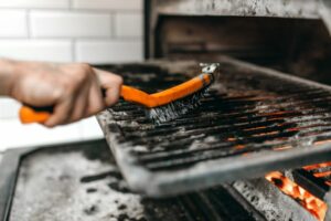 Grill wird mit einer Drahtbürste gereinigt