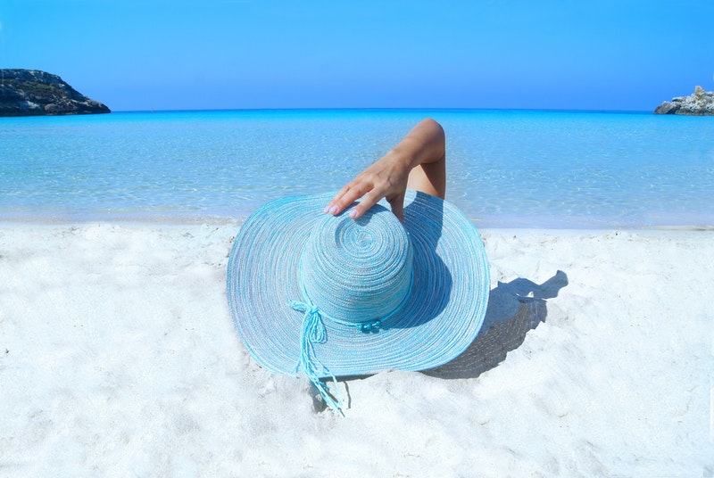 Person am Strand mit Sonnenhut