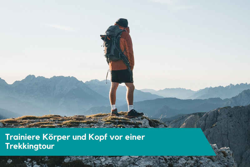 Man sieht eine Person auf einem Berg stehen. Die Person trägt Wanderausrüstung. Die Beschriftung auf dem Bild lautet: Trainiere Körper und Kopf vor einer Trekkingtour.