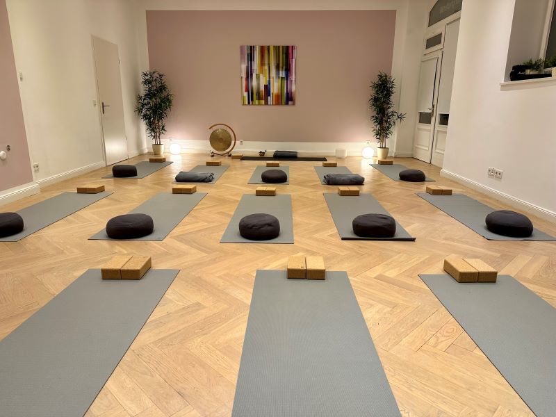 Ein heller und einladender Yoga-Raum in München, vorbereitet mit Matten, Meditationskissen und Yogablöcken.