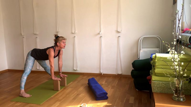 Person in einer Yogaposition, die Blöcke verwendet, in einem Yogastudio mit Wandseilen.